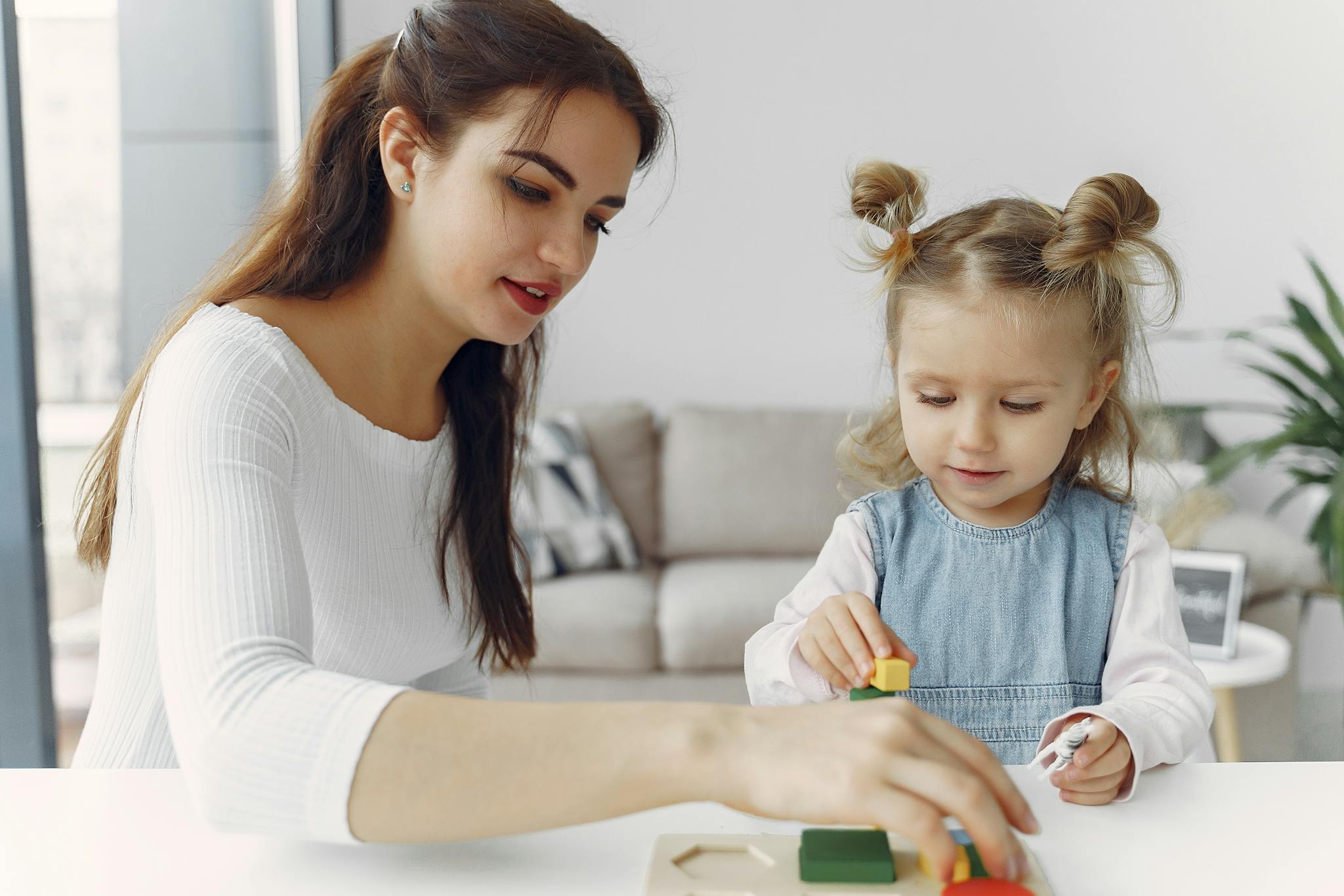 A mother and daughter bond while playing with educational toys indoors.